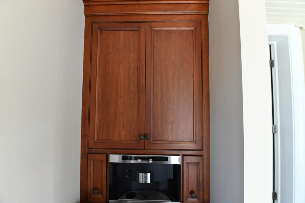 Wooden cabinet with built-in black appliance against a white wall
