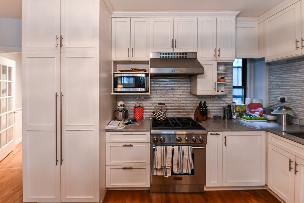 Modern kitchen with white cabinets, stainless steel appliances, and a tiled backsplash.