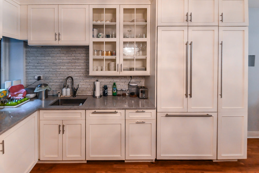 Modern kitchen with white cabinets, stainless steel appliances, and a gray backsplash.
