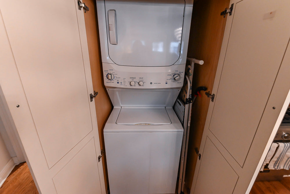 Stacked washer and dryer unit in a laundry room with cabinets.