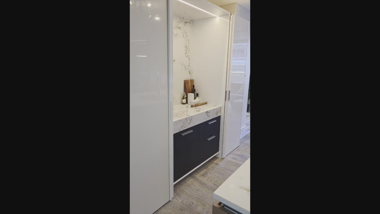 Load video: SieMatic Modern Rose Gold Handleless Island with Lotus White Hideaway Pantry with Pocket Doors